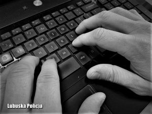 Czarno - białe zdjęcie przedstawiające dłonie mężczyzny piszącego na klawiaturze laptopa.