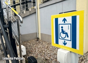 Tabliczka informująca o przycisku przywołania windy dla osób poruszających się na wózku.