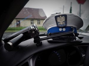 Na kokpicie radiowozu leży ręczny miernik prędkości oraz czapka policjanta Wydziału Ruchu Drogowego.